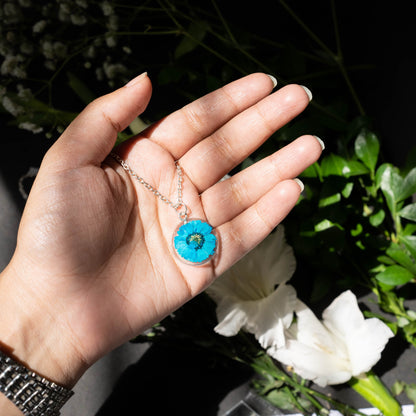 A collection of handmade resin art pendants, showcasing intricate floral designs preserved in clear resin, attached to delicate necklaces.