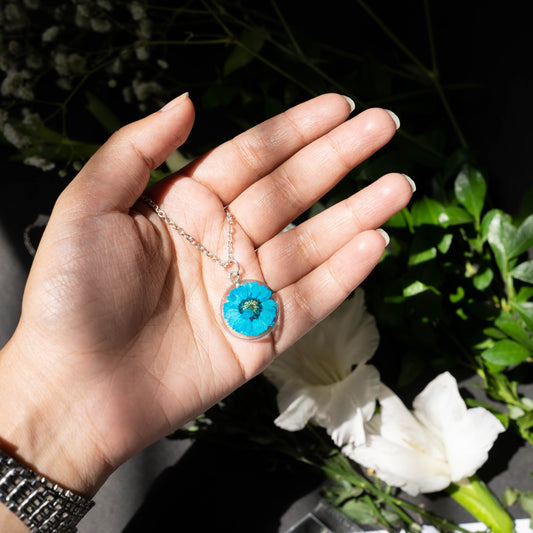 A collection of handmade resin art pendants, showcasing intricate floral designs preserved in clear resin, attached to delicate necklaces.