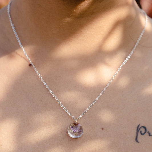A collection of handmade resin art pendants, showcasing intricate floral designs preserved in clear resin, attached to delicate necklaces.