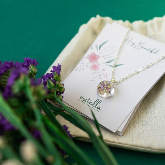A collection of handmade resin art pendants, showcasing intricate floral designs preserved in clear resin, attached to delicate necklaces.