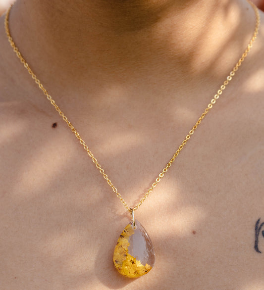 A collection of handmade resin art pendants, showcasing intricate floral designs preserved in clear resin, attached to delicate necklaces.