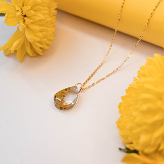 A collection of handmade resin art pendants, showcasing intricate floral designs preserved in clear resin, attached to delicate necklaces.