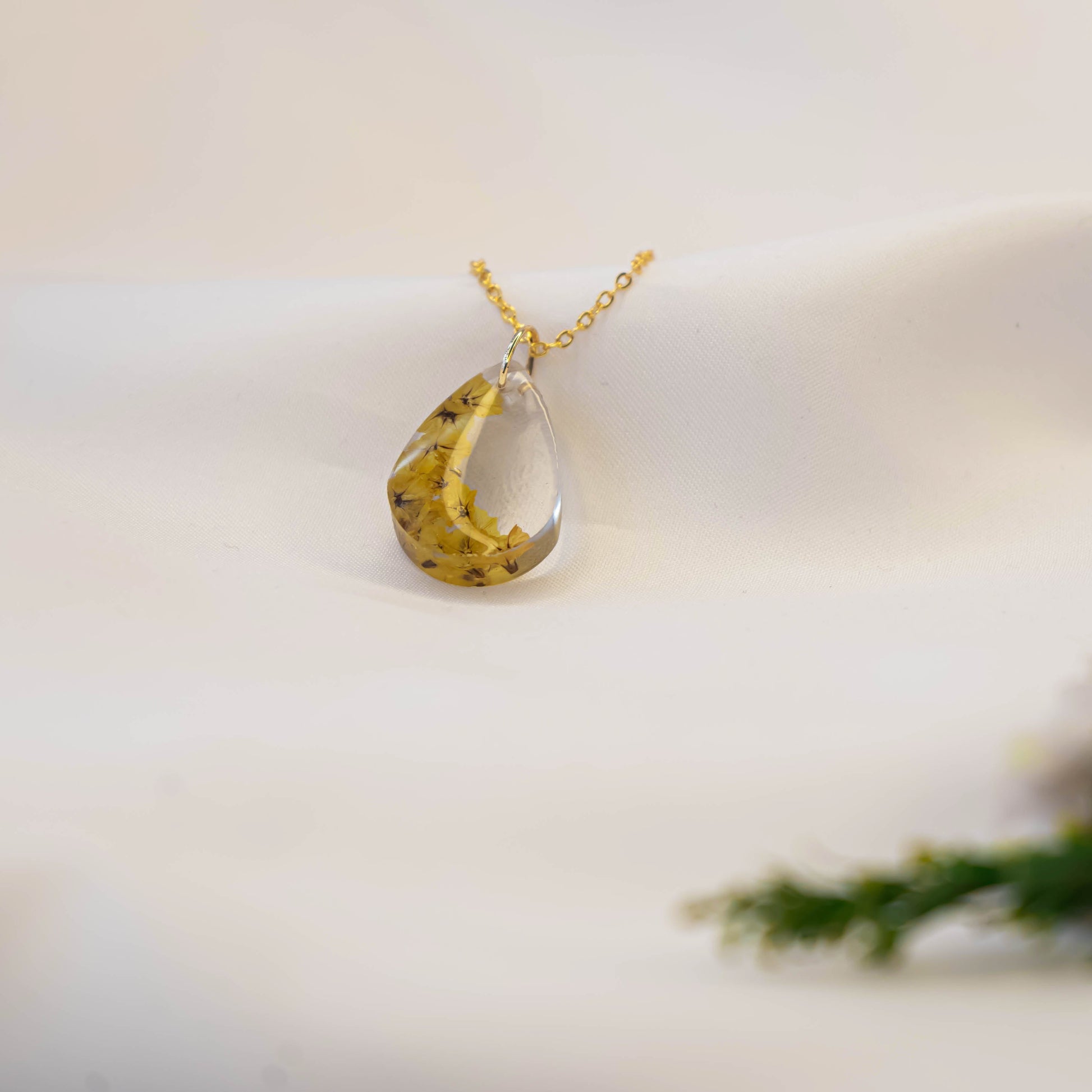 A collection of handmade resin art pendants, showcasing intricate floral designs preserved in clear resin, attached to delicate necklaces.