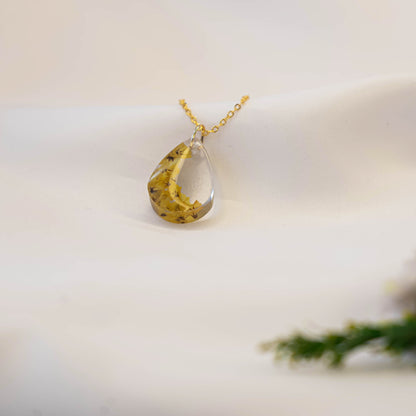 A collection of handmade resin art pendants, showcasing intricate floral designs preserved in clear resin, attached to delicate necklaces.