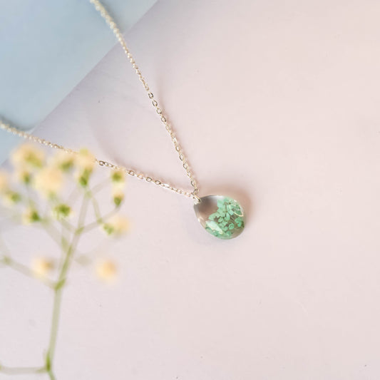 A collection of handmade resin art pendants, showcasing intricate floral designs preserved in clear resin, attached to delicate necklaces.