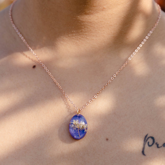 A collection of handmade resin art pendants, showcasing intricate floral designs preserved in clear resin, attached to delicate necklaces.