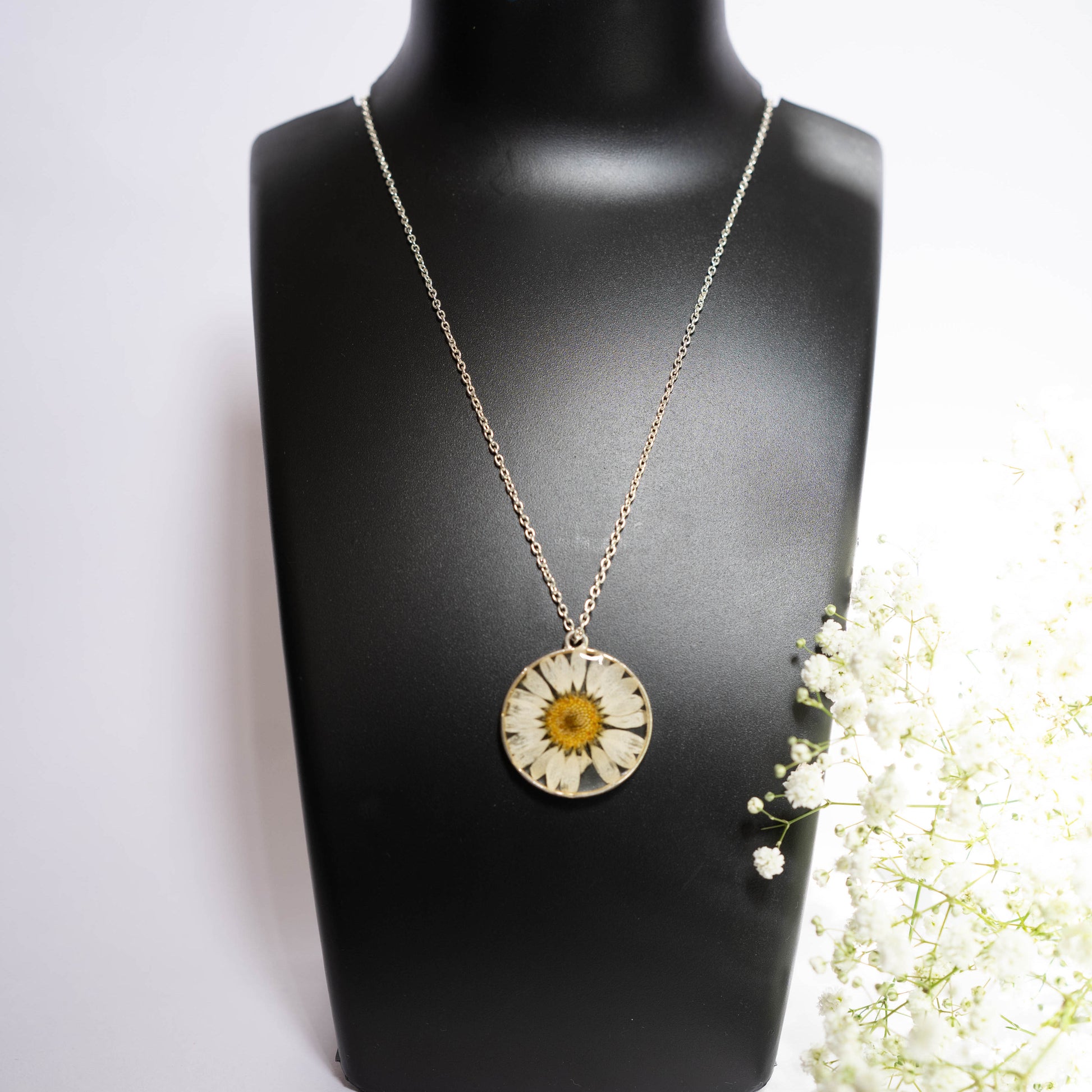 A collection of handmade resin art pendants, showcasing intricate floral designs preserved in clear resin, attached to delicate necklaces.