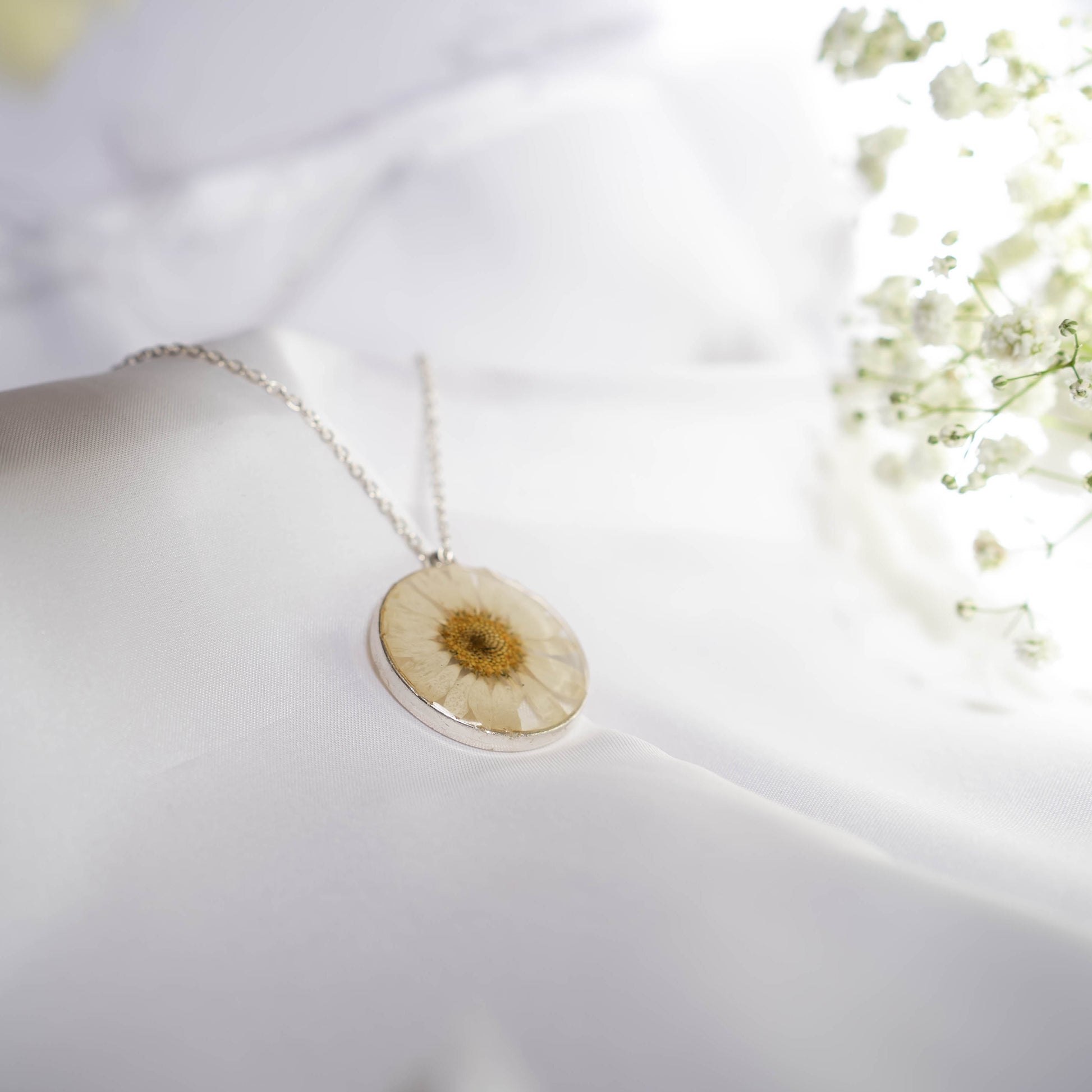 A collection of handmade resin art pendants, showcasing intricate floral designs preserved in clear resin, attached to delicate necklaces.