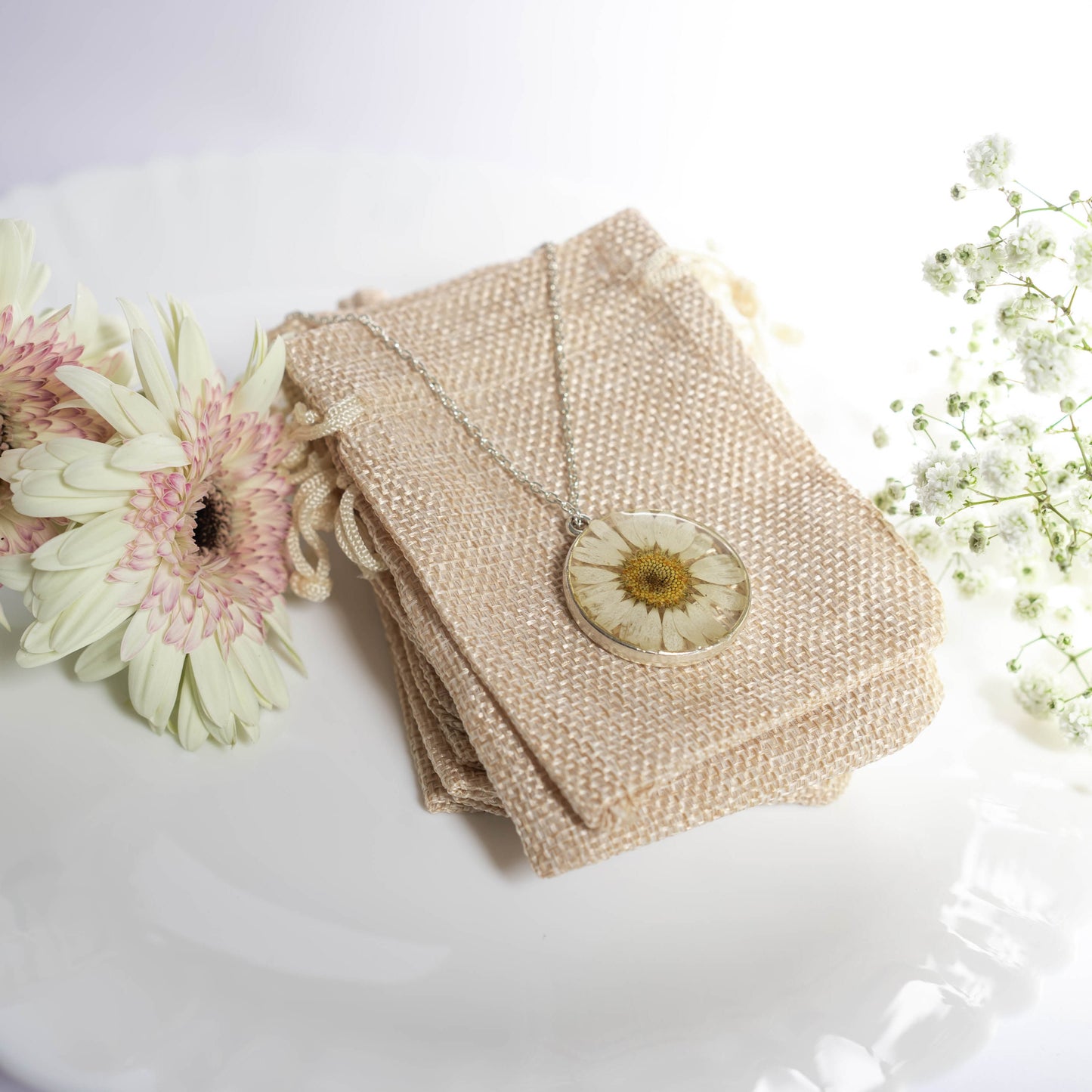 A collection of handmade resin art pendants, showcasing intricate floral designs preserved in clear resin, attached to delicate necklaces.