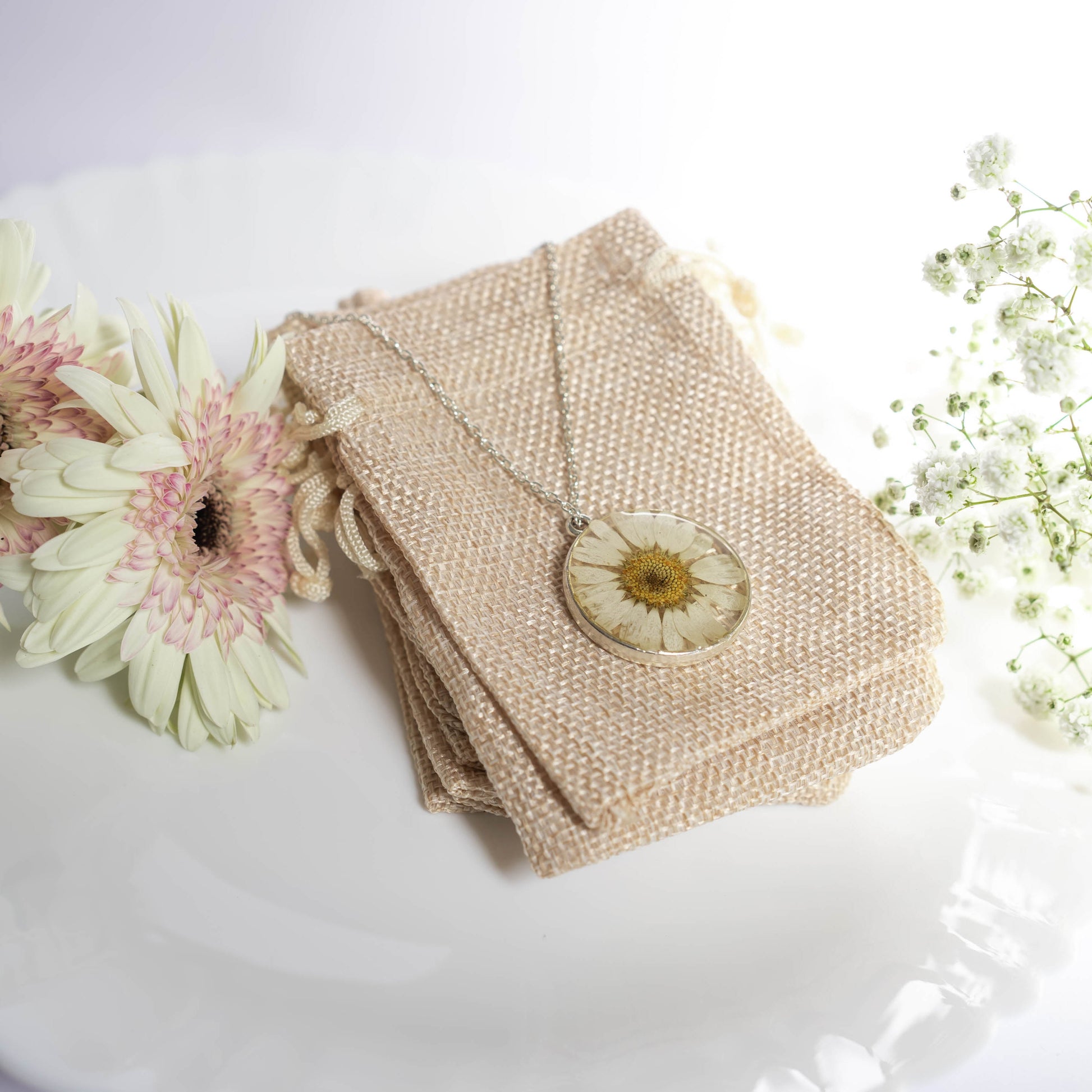 A collection of handmade resin art pendants, showcasing intricate floral designs preserved in clear resin, attached to delicate necklaces.