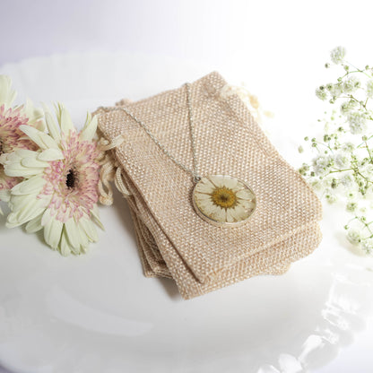 A collection of handmade resin art pendants, showcasing intricate floral designs preserved in clear resin, attached to delicate necklaces.