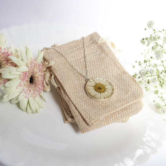 A collection of handmade resin art pendants, showcasing intricate floral designs preserved in clear resin, attached to delicate necklaces.