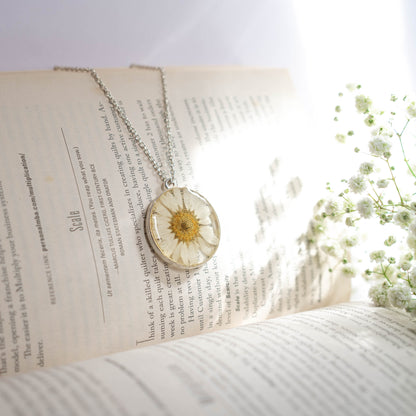 A collection of handmade resin art pendants, showcasing intricate floral designs preserved in clear resin, attached to delicate necklaces.