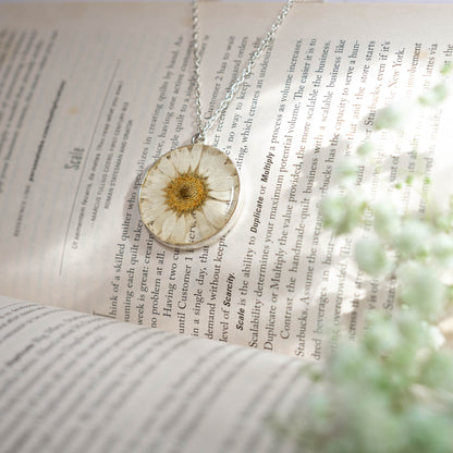 A collection of handmade resin art pendants, showcasing intricate floral designs preserved in clear resin, attached to delicate necklaces.