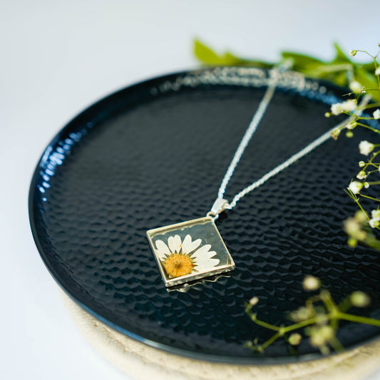 A collection of handmade resin art pendants, showcasing intricate floral designs preserved in clear resin, attached to delicate necklaces.