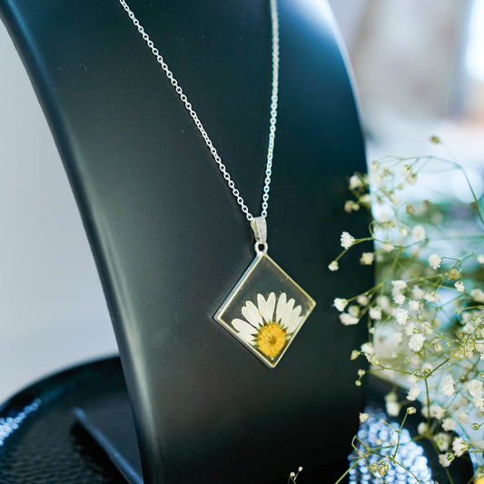 A collection of handmade resin art pendants, showcasing intricate floral designs preserved in clear resin, attached to delicate necklaces.