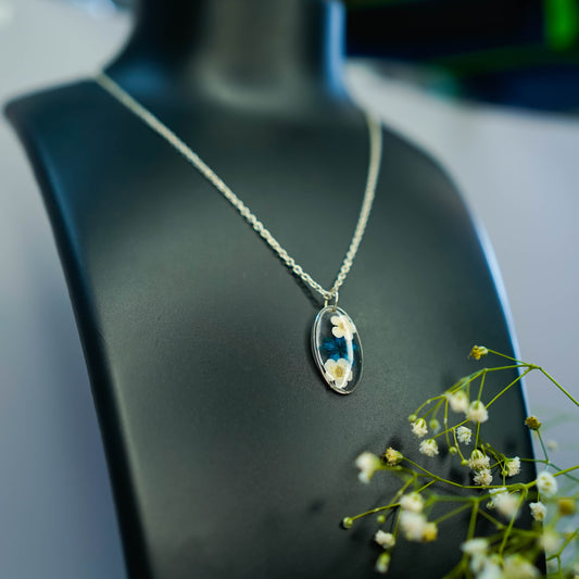 A collection of handmade resin art pendants, showcasing intricate floral designs preserved in clear resin, attached to delicate necklaces.