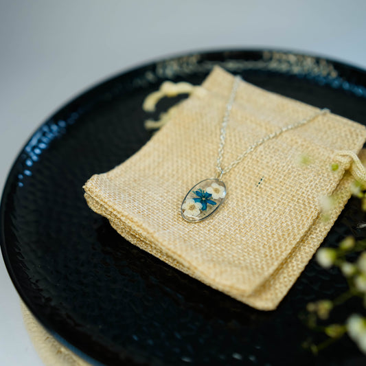 A collection of handmade resin art pendants, showcasing intricate floral designs preserved in clear resin, attached to delicate necklaces.
