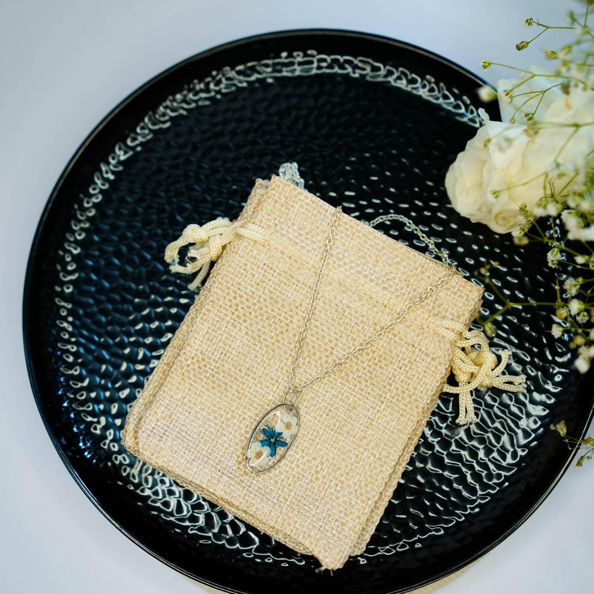 A collection of handmade resin art pendants, showcasing intricate floral designs preserved in clear resin, attached to delicate necklaces.