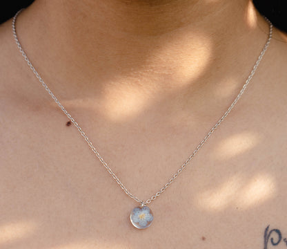 A collection of handmade resin art pendants, showcasing intricate floral designs preserved in clear resin, attached to delicate necklaces.