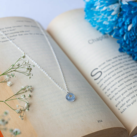 A collection of handmade resin art pendants, showcasing intricate floral designs preserved in clear resin, attached to delicate necklaces.