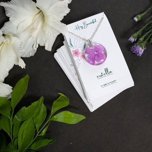 A collection of handmade resin art pendants, showcasing intricate floral designs preserved in clear resin, attached to delicate necklaces.