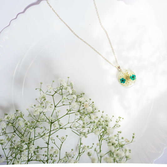 A collection of handmade resin art pendants, showcasing intricate floral designs preserved in clear resin, attached to delicate necklaces.