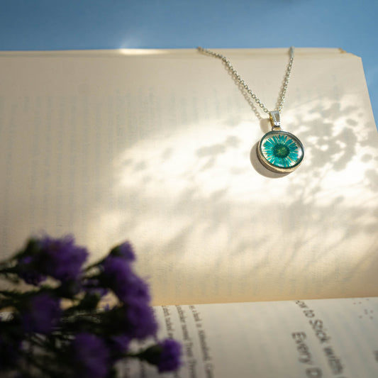 A collection of handmade resin art pendants, showcasing intricate floral designs preserved in clear resin, attached to delicate necklaces.