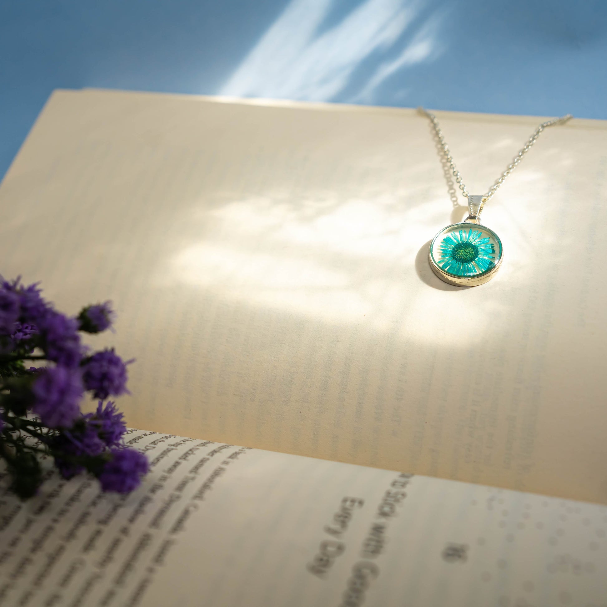 A collection of handmade resin art pendants, showcasing intricate floral designs preserved in clear resin, attached to delicate necklaces.