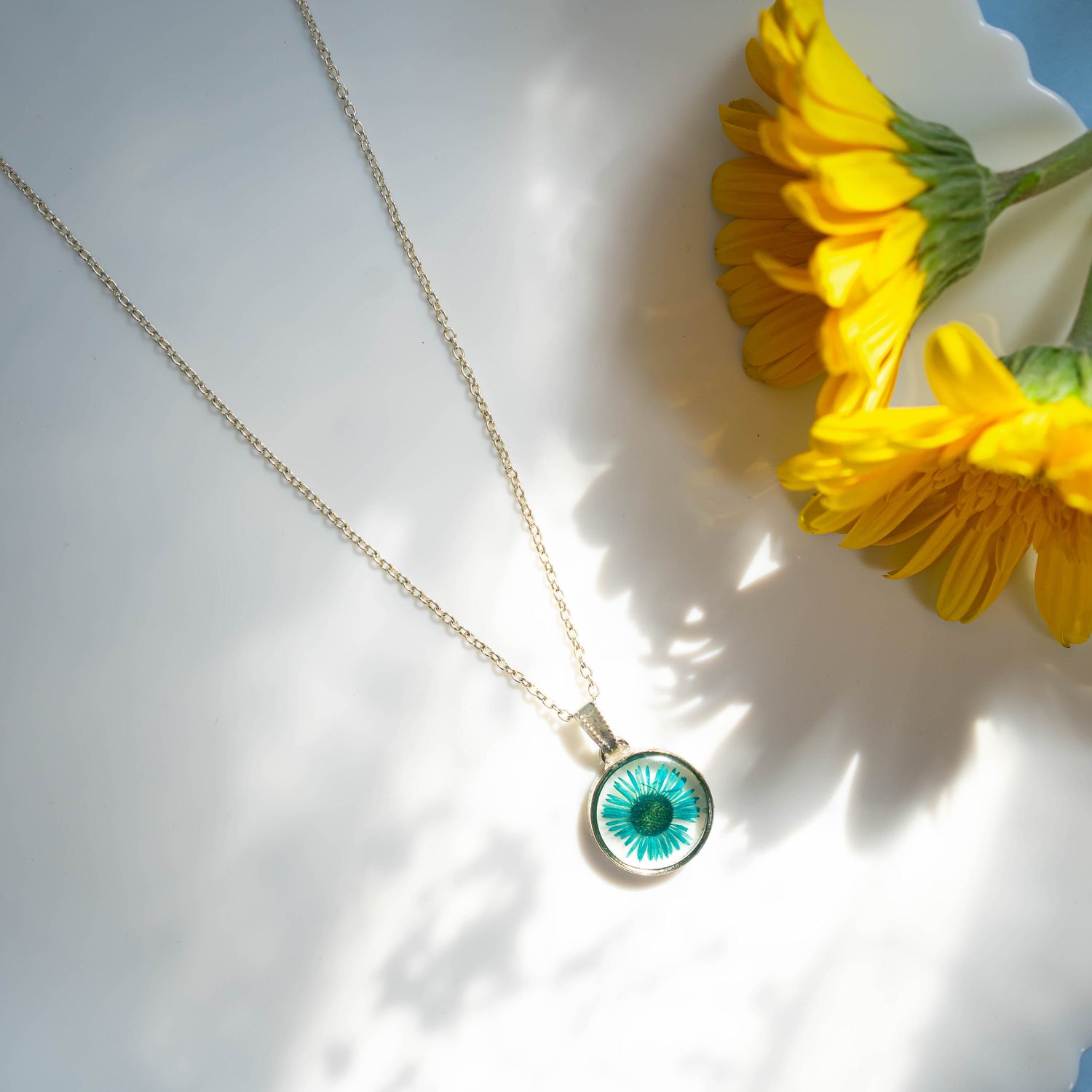 A collection of handmade resin art pendants, showcasing intricate floral designs preserved in clear resin, attached to delicate necklaces.